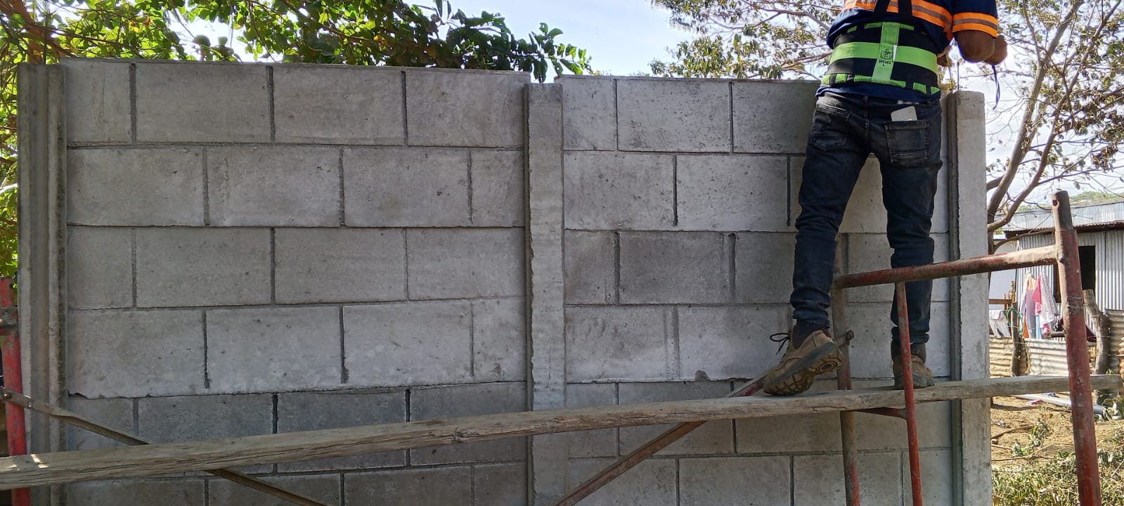 Trabajador instalando muros prefabricados con andamio profesional
